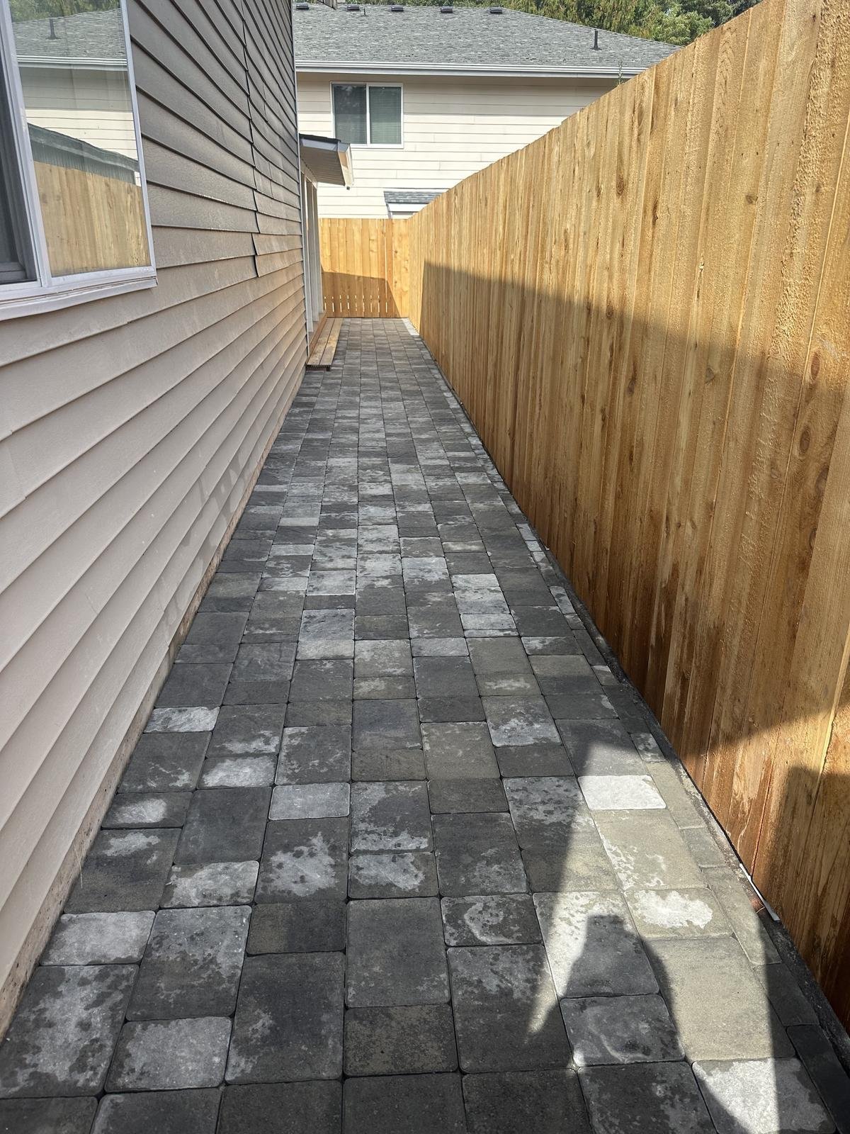 Struver paver walkway between a cedar privacy fence and a residential home with light grey siding